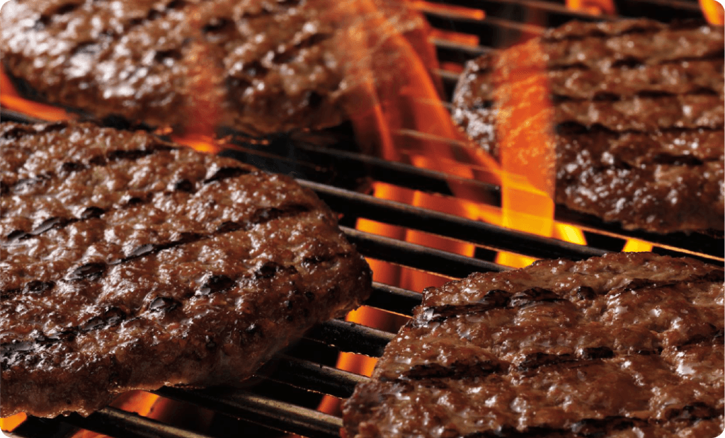 ブロイラーを用いてビーフパティを直接火で焼いている様子
